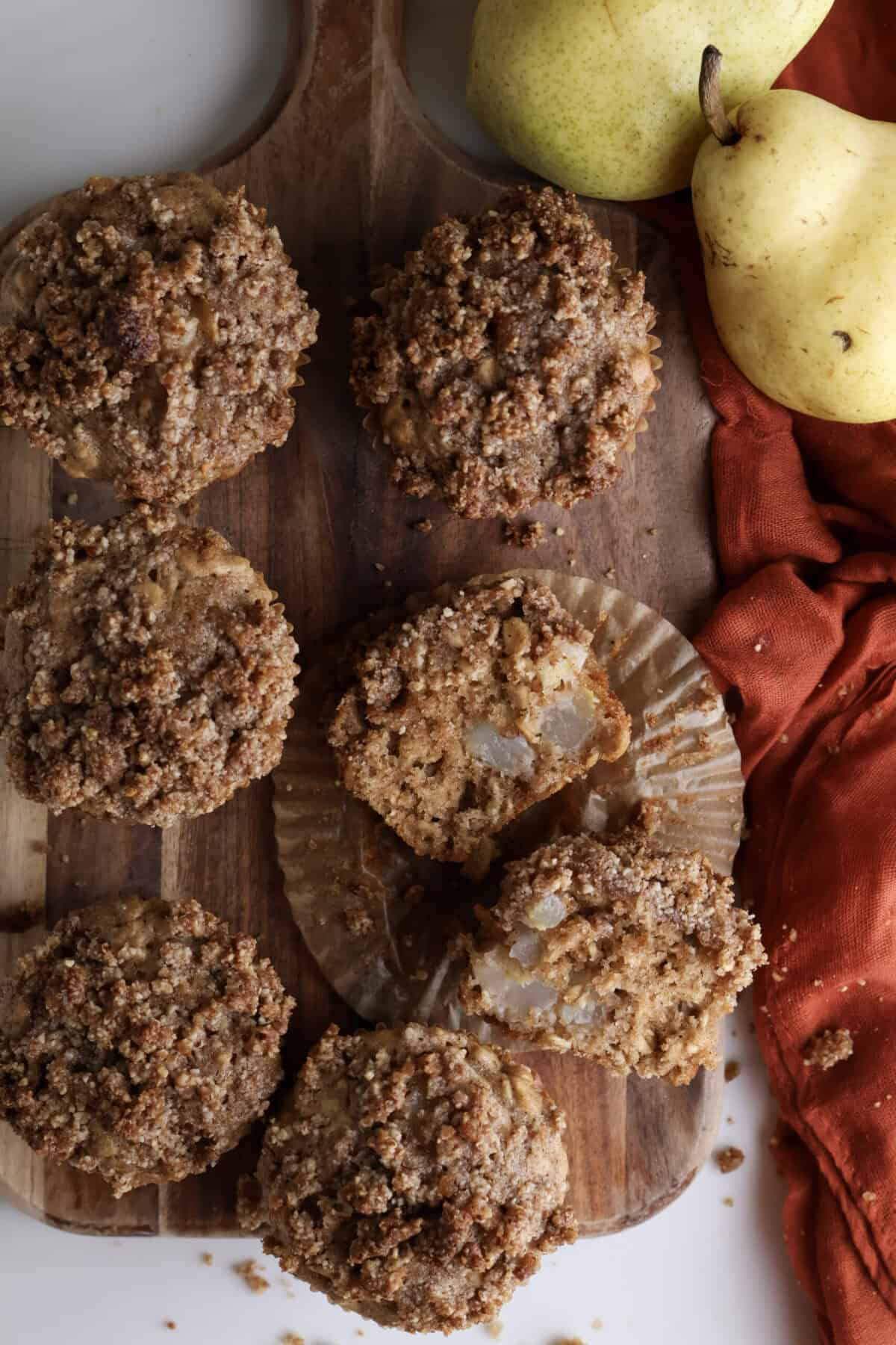Oat Pear Muffins with Pecan Streusel on a wooden cutting board.