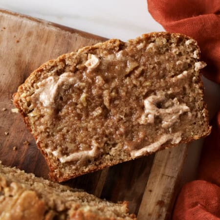 Slice of apple bread with cinnamon sugar butter spread on it.