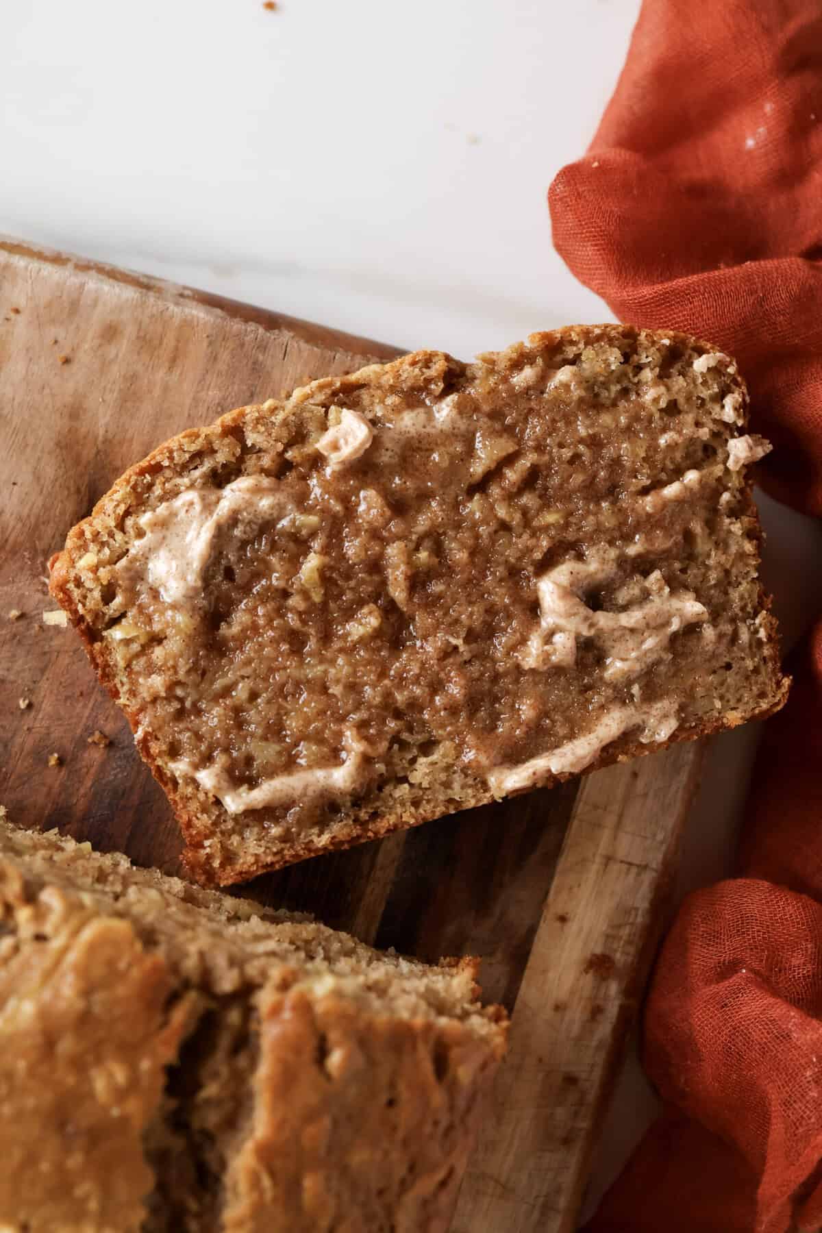 Slice of apple bread with cinnamon sugar butter spread on it.