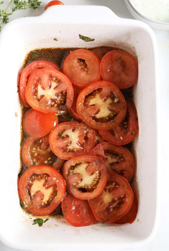Sliced tomatoes in a dish marinating for the ricotta toast.