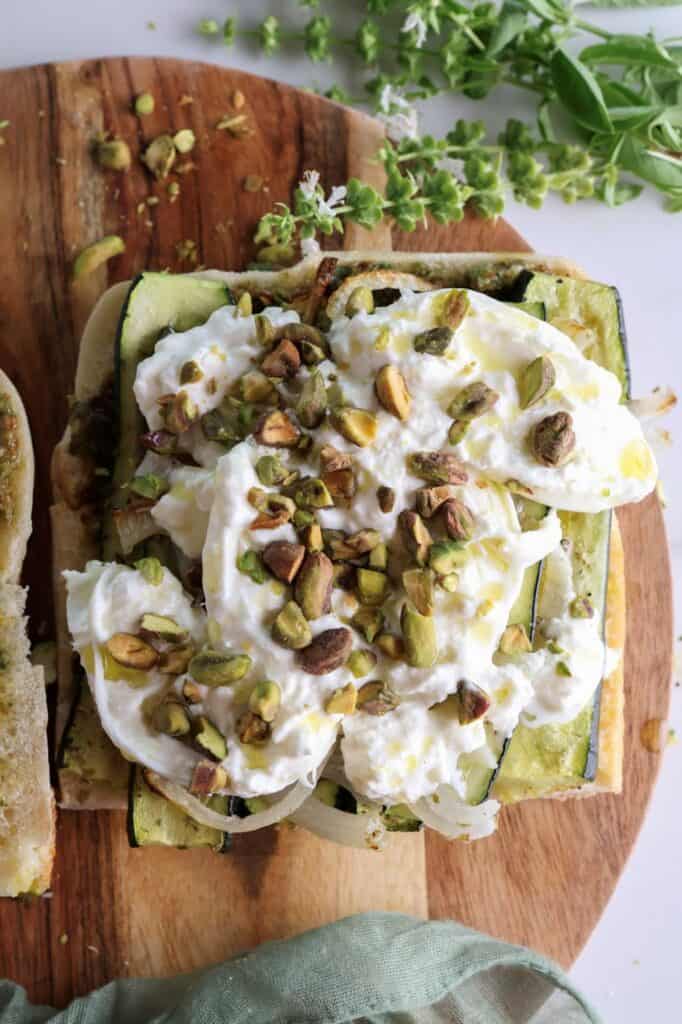 Open roasted vegetable sandwich with the burrata cheese, olive oil, and pistachios.