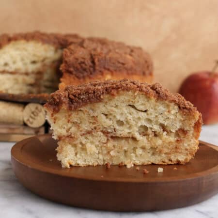 Slice of apple coffee cake on a wood plate.