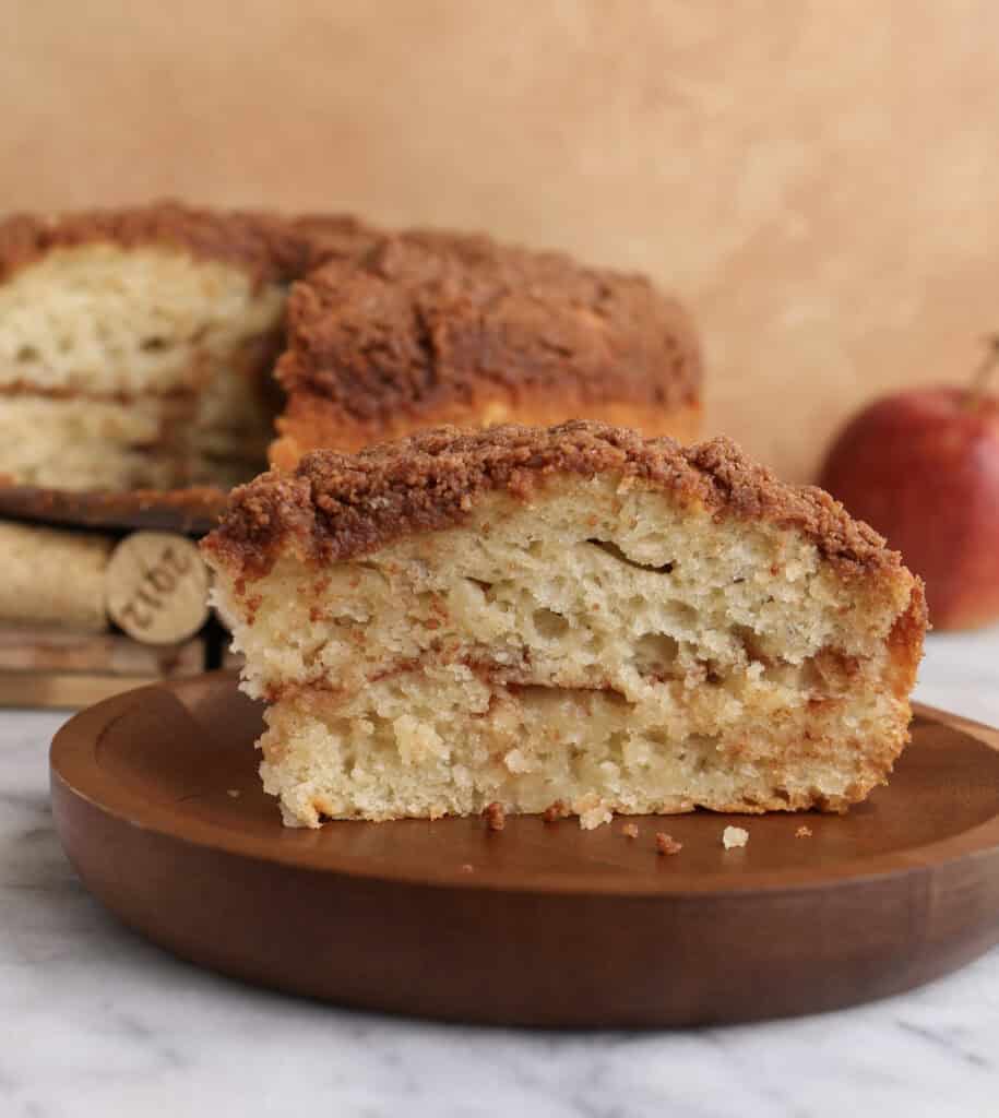 Slice of apple coffee cake on a wood plate.