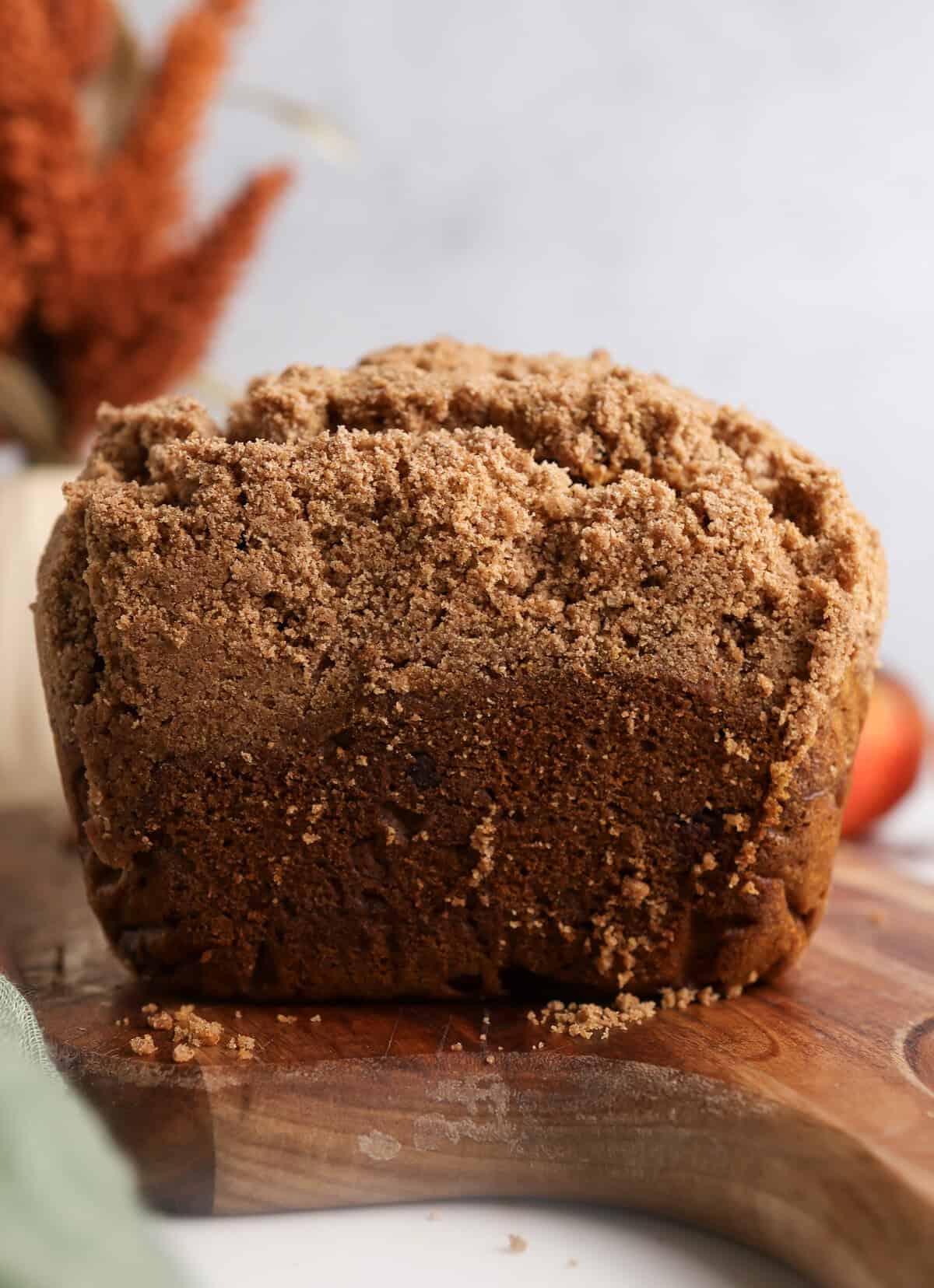 Up close of the pumpkin chocolate chip bread with crumb topping on a cutting board. 