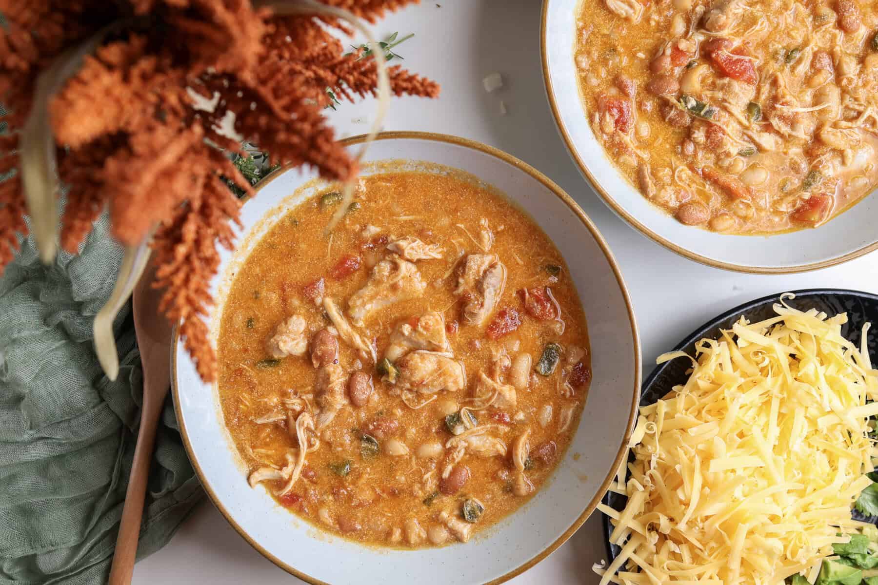 Buffalo chicken chili in bowls with a plate of topping sitting off the the side.