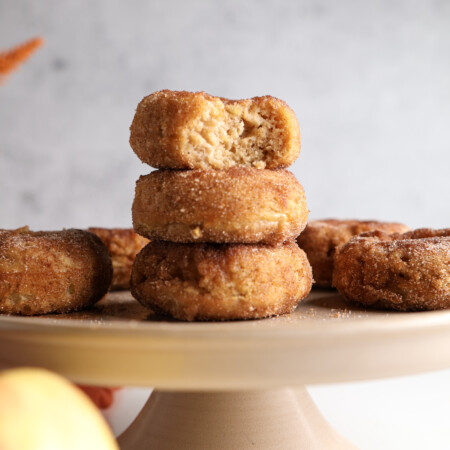 Apple baked donuts with cinnamon sugar stacked on each other.