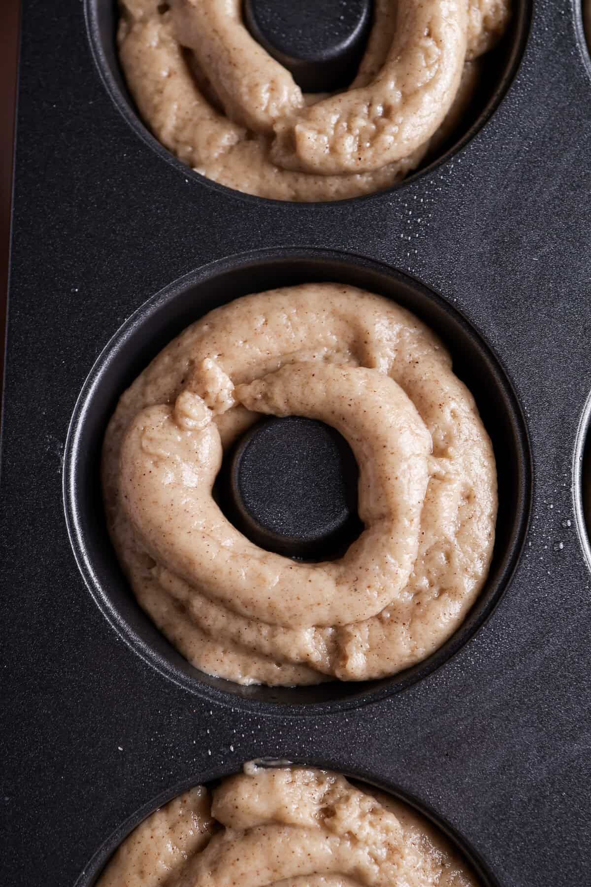 Spiced baked donut batter in a donut pan before being baked.