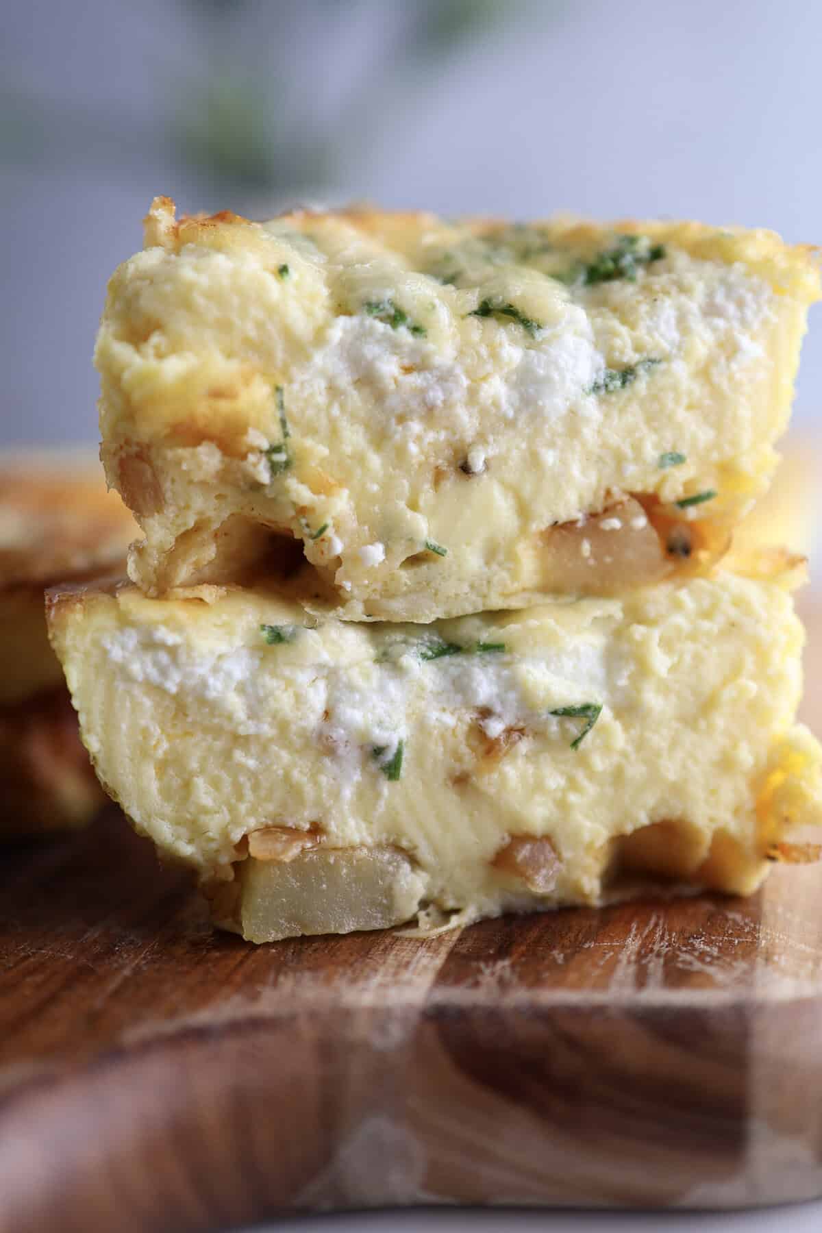Up close shot of the cottage cheese egg bites cut in half, showing the potatoes, chives and goat cheese. 