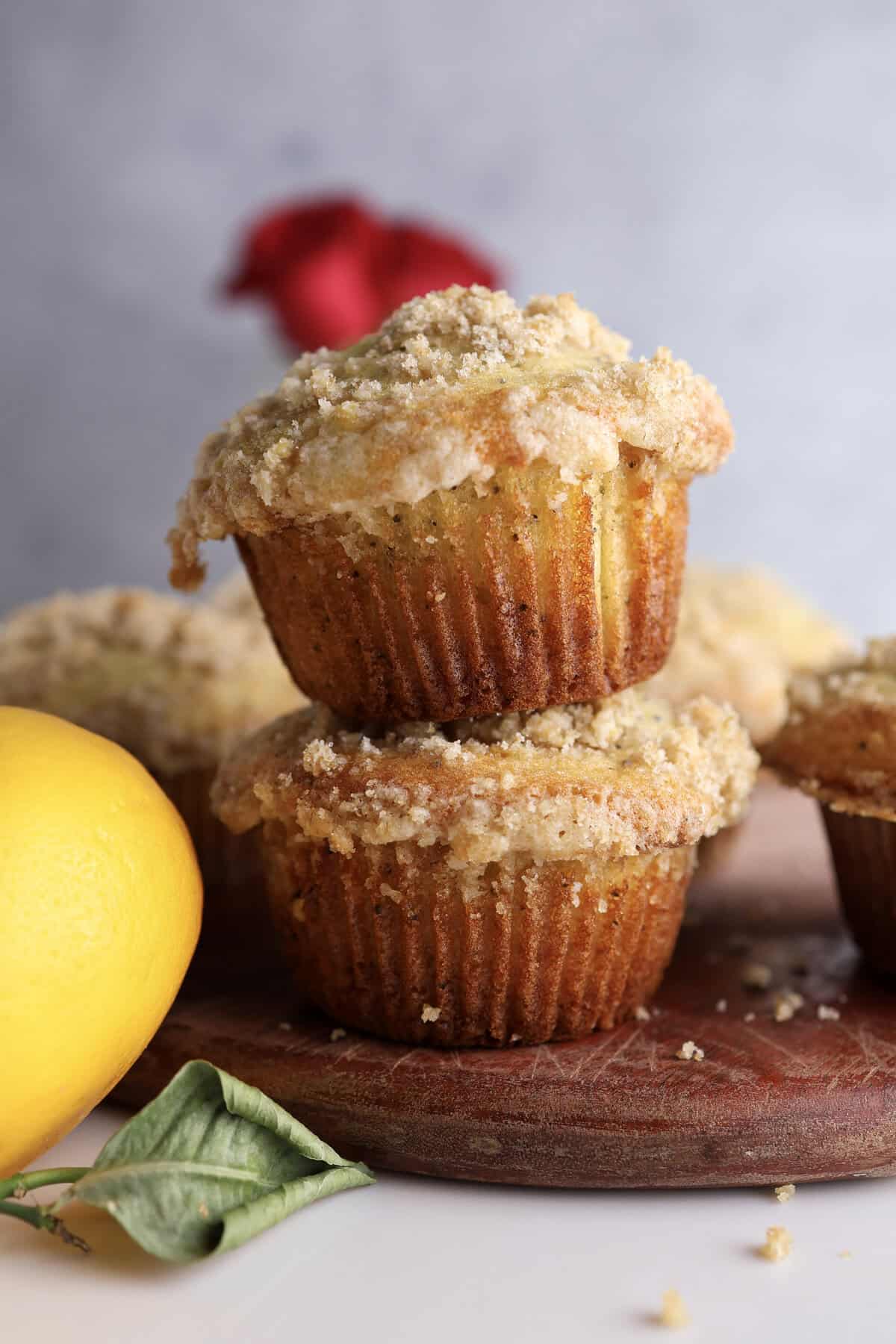 Two lemon poppy seed muffins stacked on each other on a cutter board.