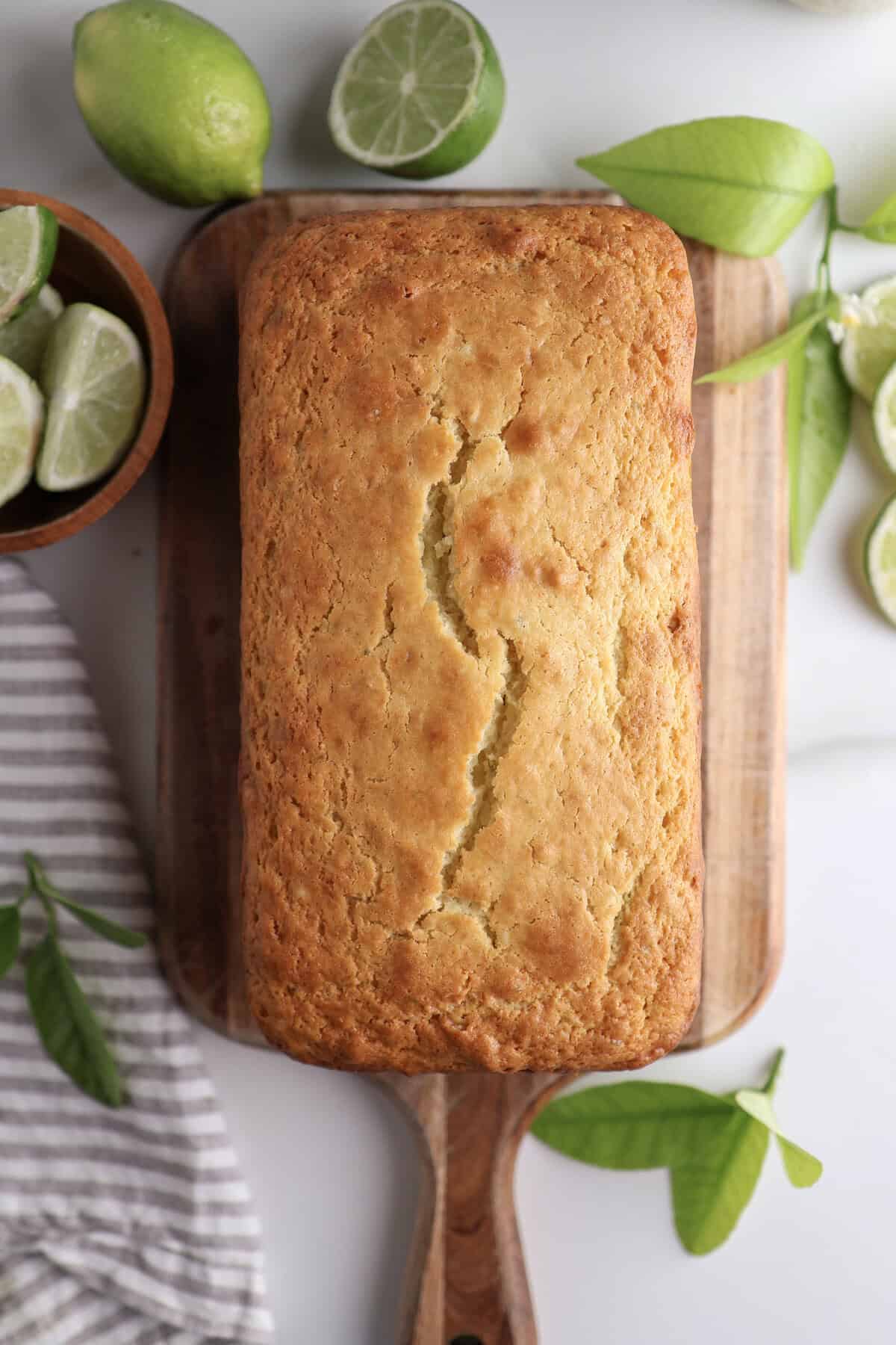 Ricotta lime loaf on a cutting board with fresh limes sitting next to it.