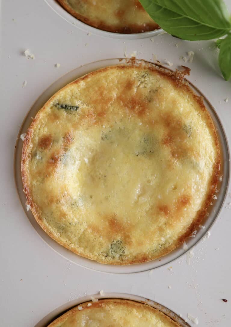 Up close of a baked ricotta egg bite right out of the oven still in a muffin tin.