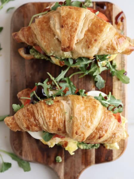 caprese breakfast croissant sandwiches sitting on a cutting board.