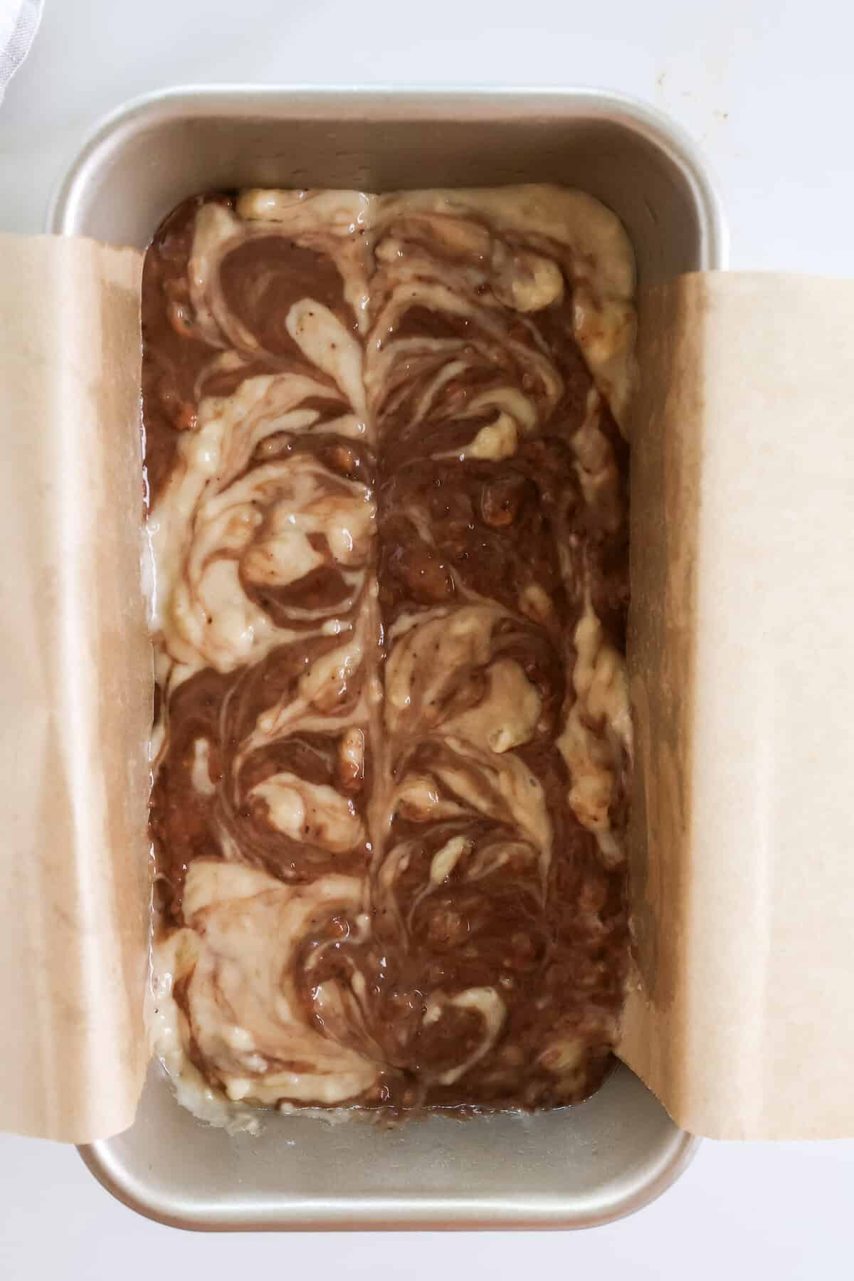Unbaked marbled banana bread showing the chocolate and plain banana bread batter swirled together in a loaf pan.