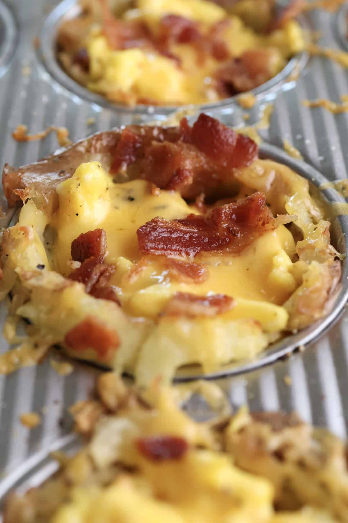 Loaded smashed potato breakfast cup right out of the oven with melted cheese and bacon