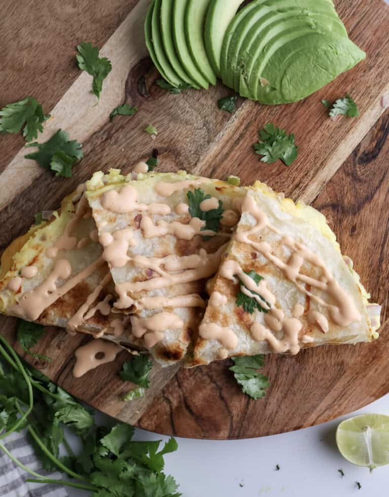 Breakfast Quesadilla with chipotle sliced on a cutting board with avocado and cilantro