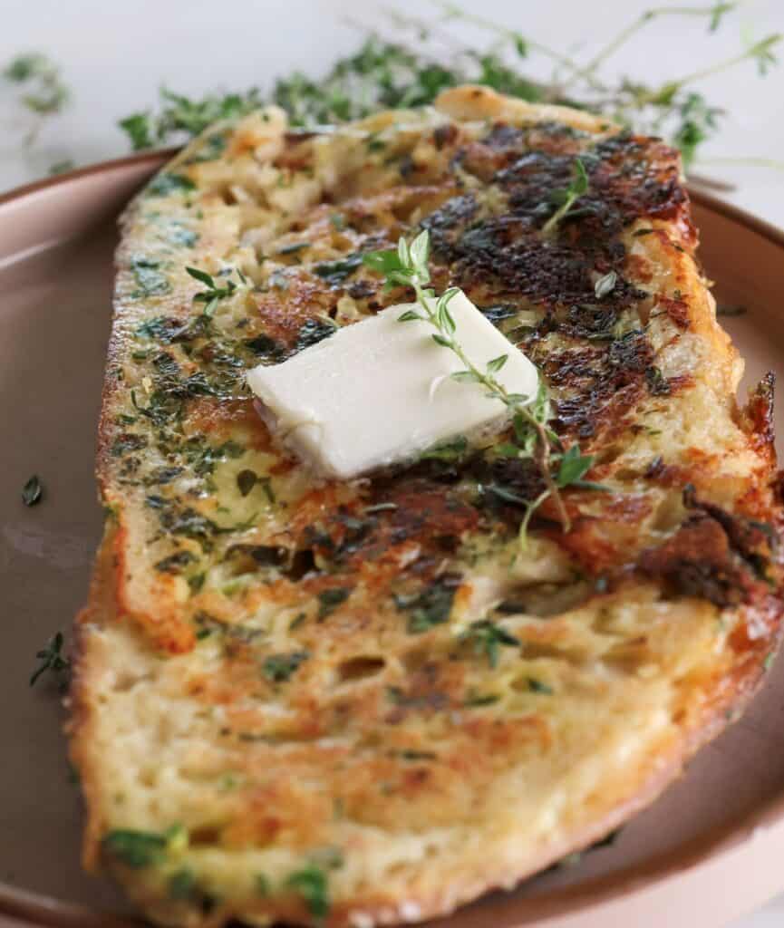 An up-close shot of the cooked savory French toast with a pat of butter.