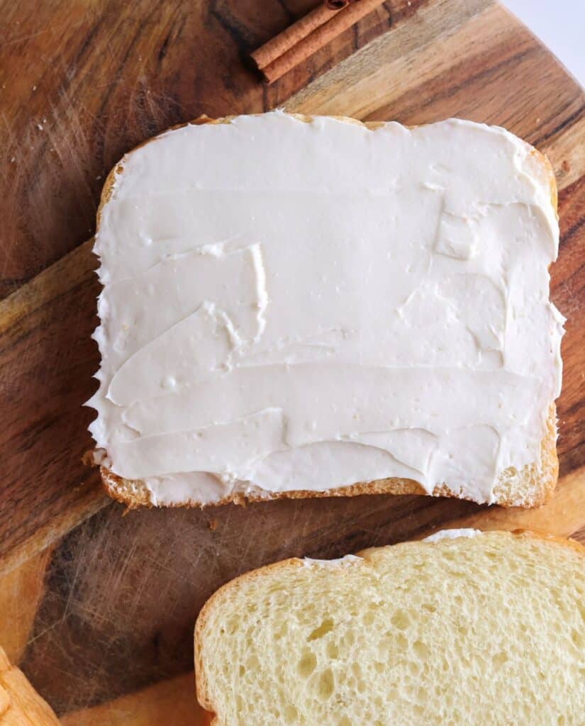 Cream cheese spread out on brioche bread slice for the pumpkin French toast. 