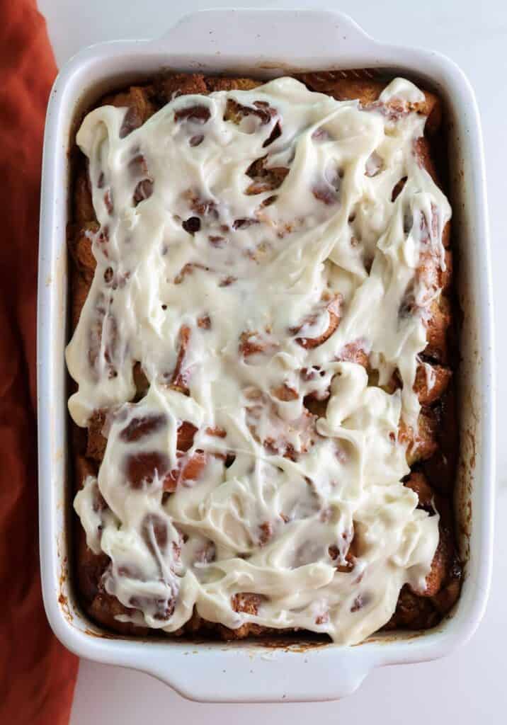 Cinnamon Roll Brioche French Toast Casserole with cream cheese frosting spread on top.
