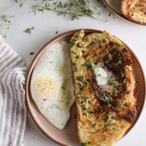 Overhead shot of the savory parmesan and herb French toast with a fried egg on the side.