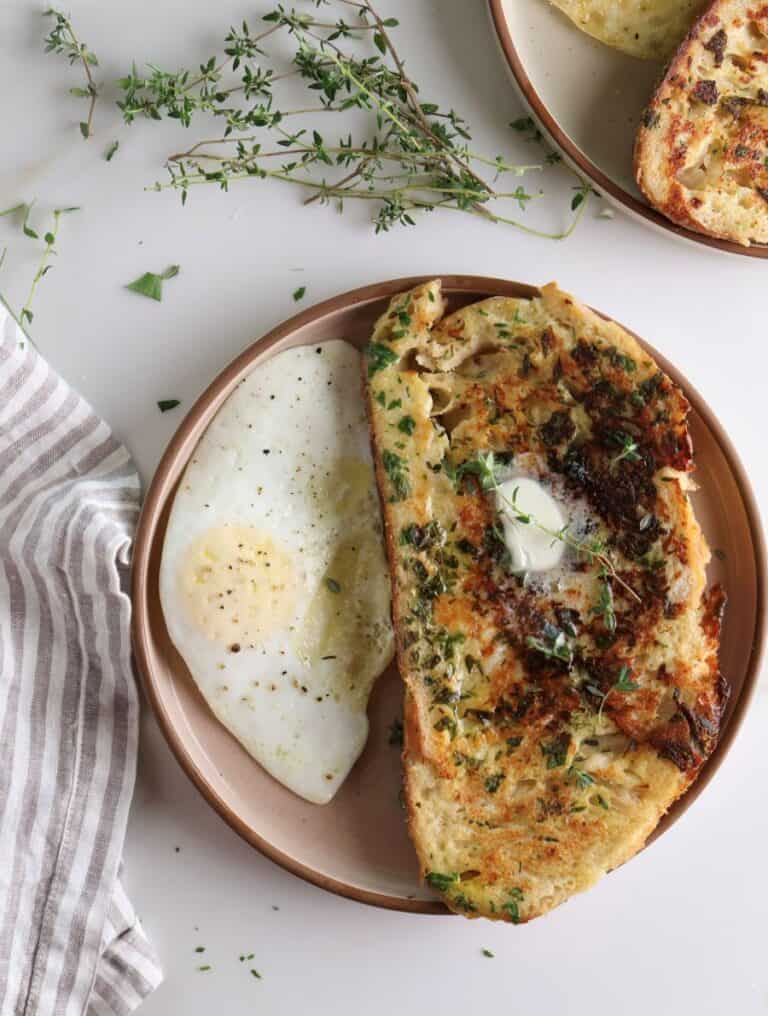 Overhead shot of the savory parmesan and herb French toast with a fried egg on the side.