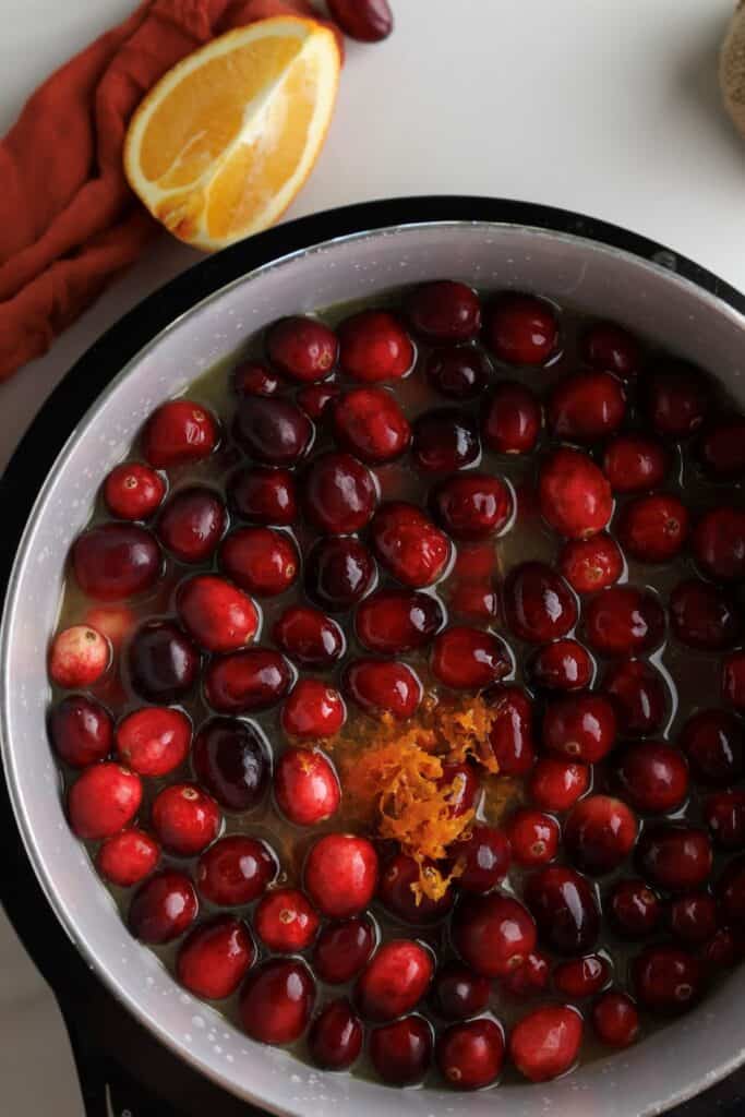 The cranberry and orange sauce ingredients on a saucepan before being cooked.