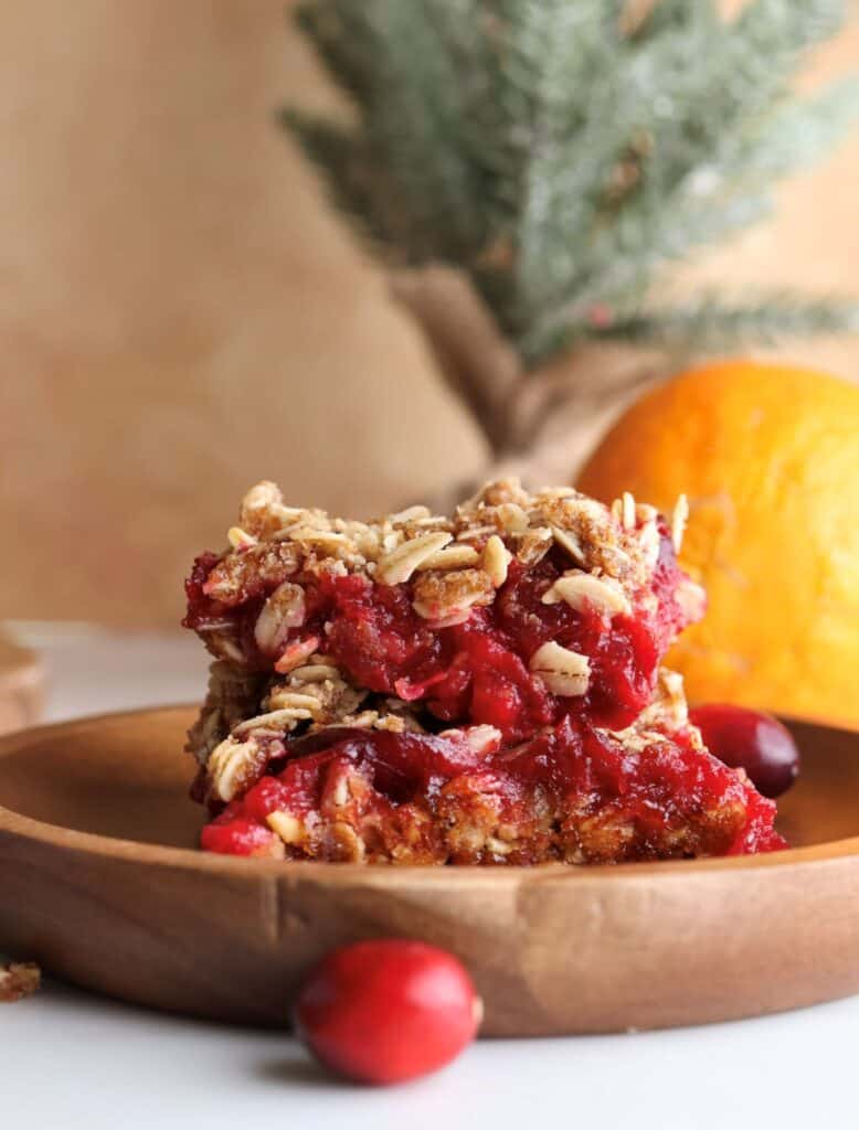 Stacked cranberry and orange oat bars on a plate.