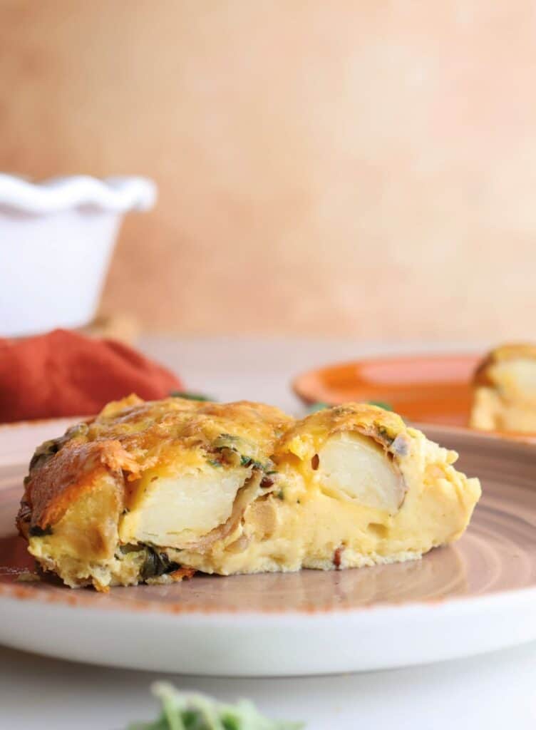 Side view of a slice of the roasted potato breakfast bake on a plate.