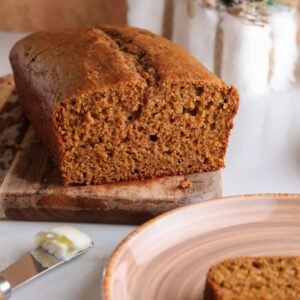Sliced spiced gingerbread loaf with Greek yogurt on a cutting board.