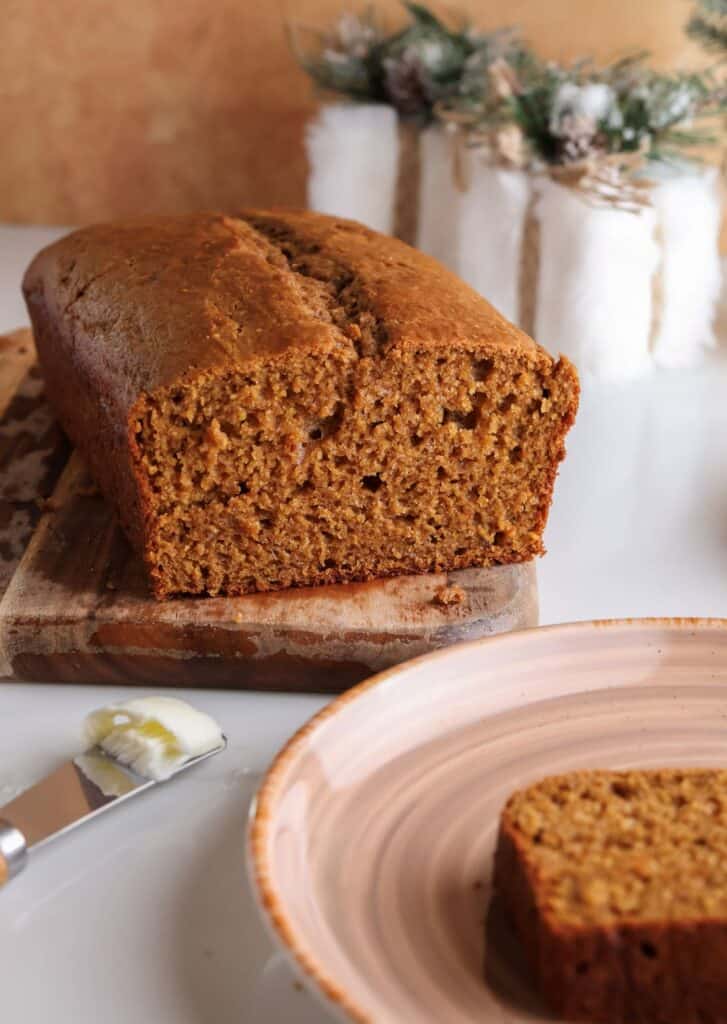 Sliced spiced gingerbread loaf with Greek yogurt on a cutting board.