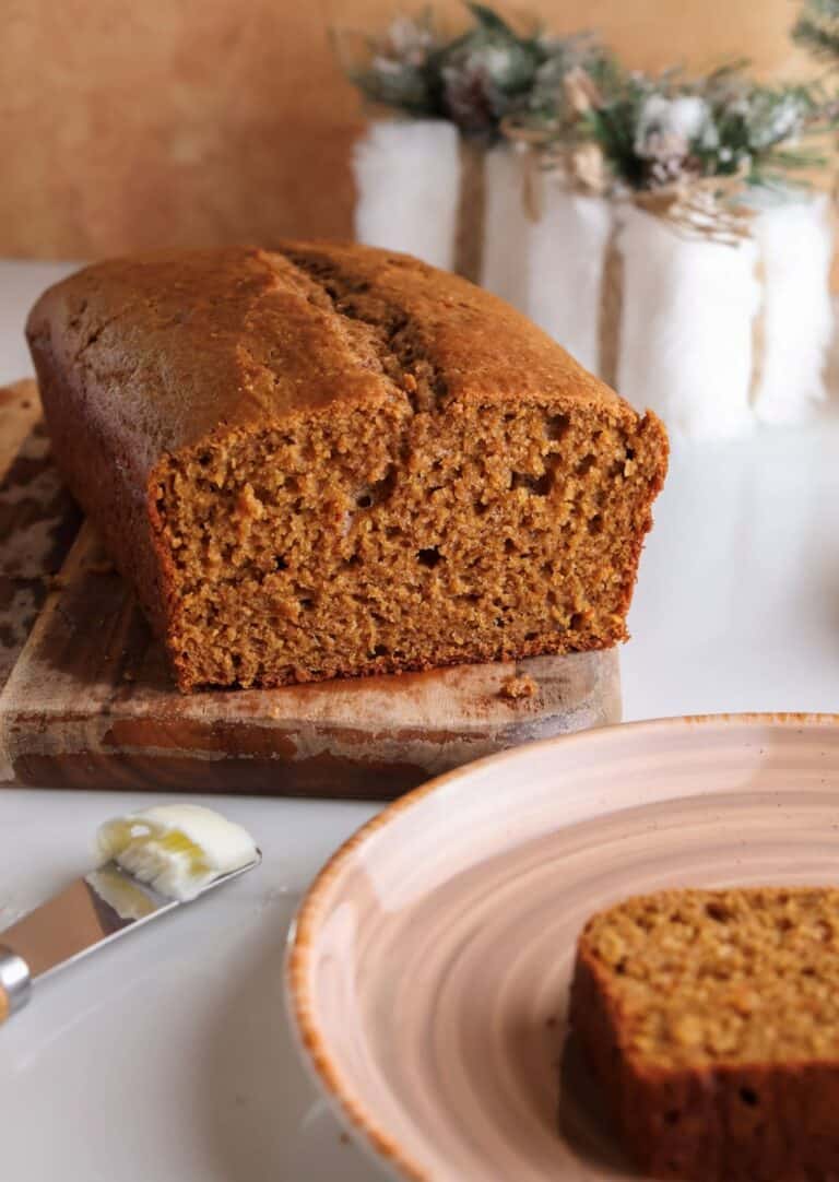 Sliced spiced gingerbread loaf with Greek yogurt on a cutting board.