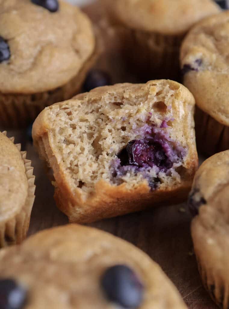 Protein blueberry lemon muffin with a bite in it on a cutting board.