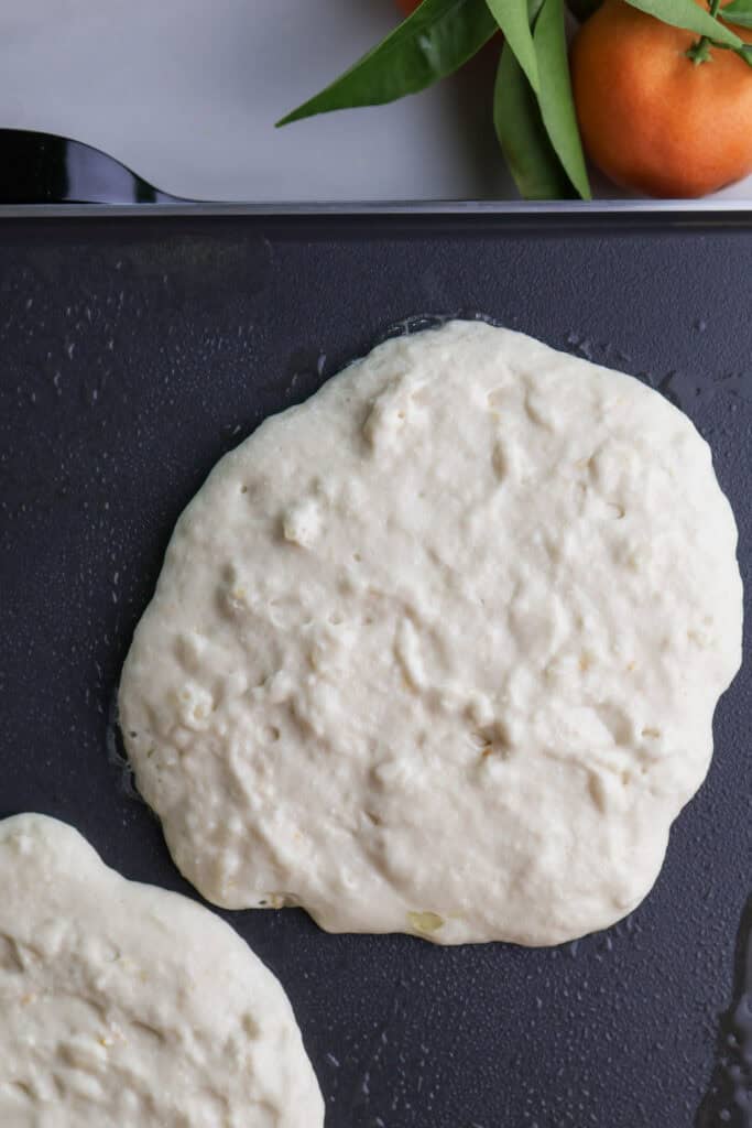 Ricotta orange pancake batter on a griddle cooking.