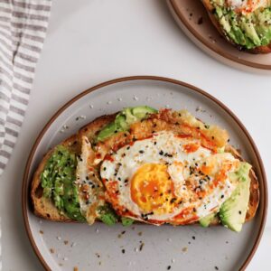 Spicy avocado toast with fried egg on plate.