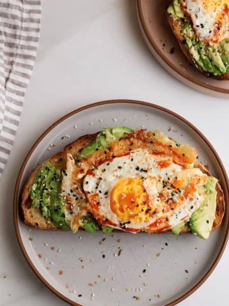 Spicy avocado toast with fried egg on plate.