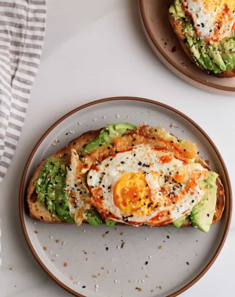 Spicy avocado toast with fried egg on plate.