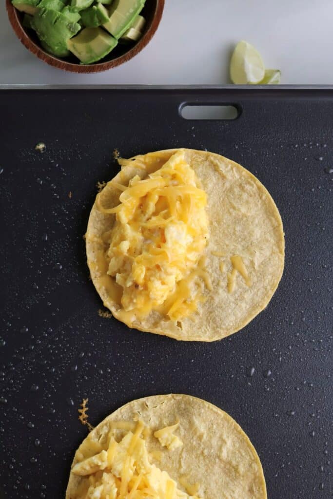 Breakfast tacos with scrambled eggs cooking on the griddle. 