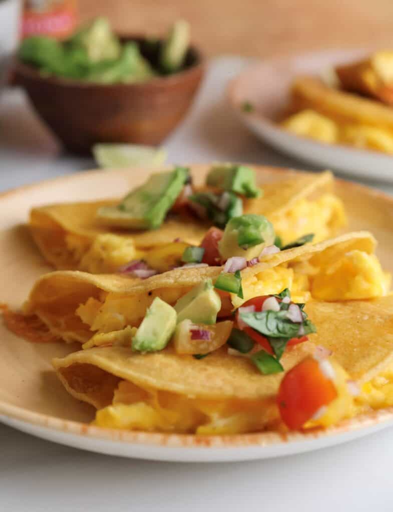 The breakfast egg tacos on a plate with pico de gallo. 