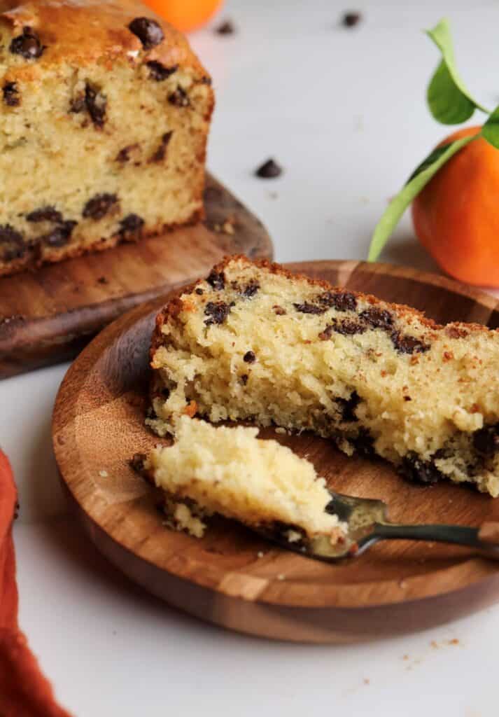 Slice of orange and chocolate chip bread on plate with a fork cutting into the loaf.