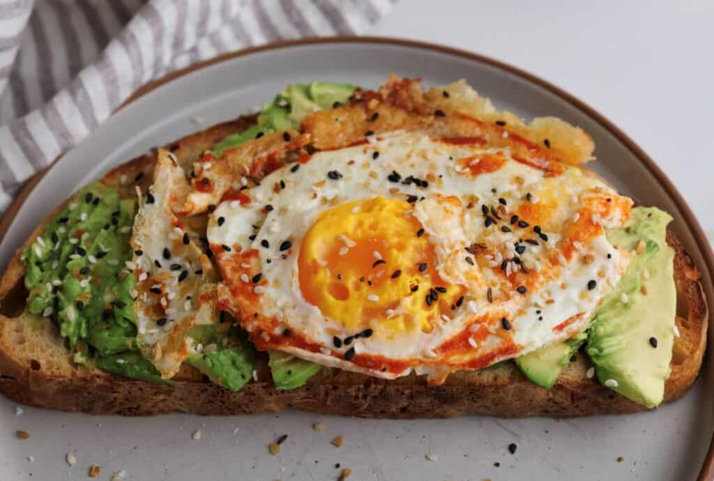 Up close shot of the spicy avocado toast with fried egg on a plate.