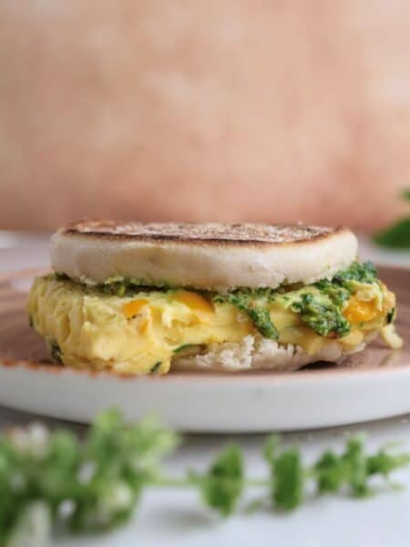 Freezer breakfast sandwich with pistachio pesto on a plate.