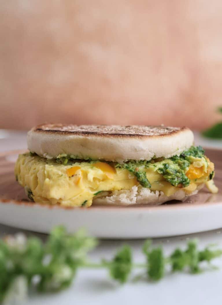 Freezer breakfast sandwich with pistachio pesto on a plate.