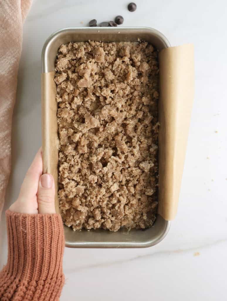 Banana bread with crumble topping in bread pan before going in the oven.