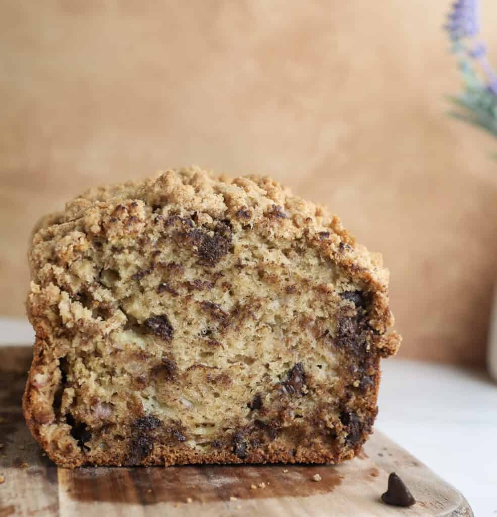 Chocolate chip banana bread with crumble on cutting board cut open.