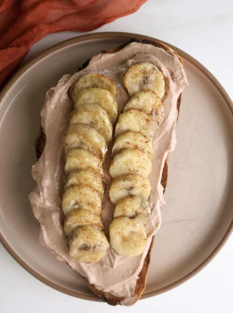 Chocolate cottage cheese mouse toast topped with air fryer bananas on a plate.