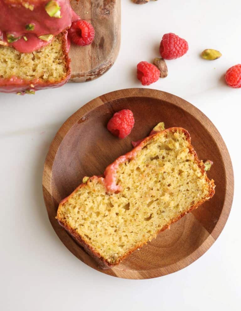 Slice of lemon pistachio loaf cake raspberry glaze on a plate.