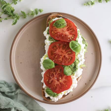 Avocado toast with cottage cheese and tomatoes on a plate.