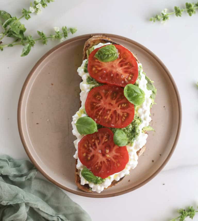 Avocado toast with cottage cheese and tomatoes on a plate.