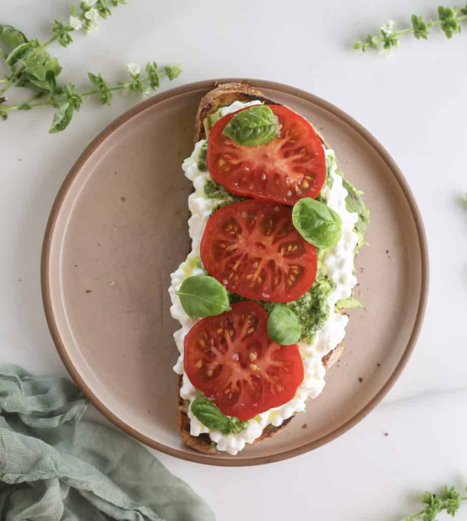 Avocado toast with cottage cheese and tomatoes on a plate.
