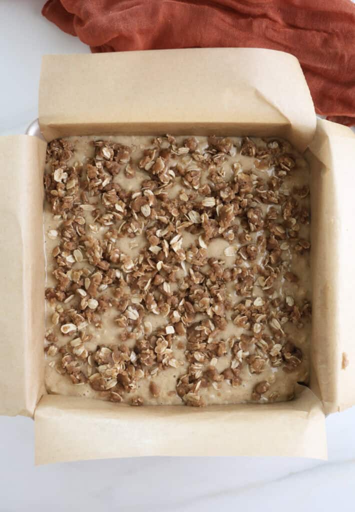 The oatmeal coffee cake batter with oat topping in a baking pan before going into the oven.