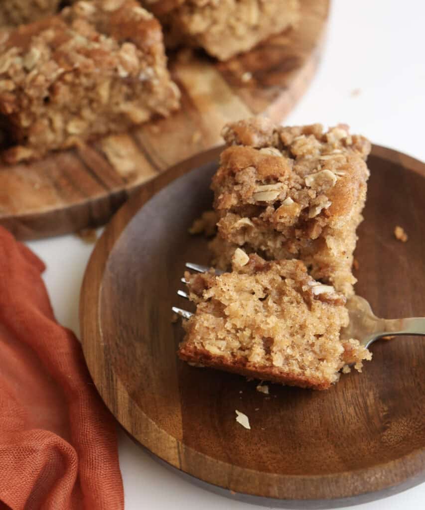 A slice of spiced oatmeal coffee cake on a plate with a fork.